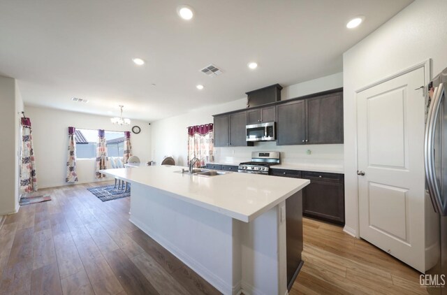 10213 Breitenbush Ave, Bakersfield, CA 93311 - kitchen with stainless steel appliances, a sink, a center island with sink, a chandelier, and dark brown cabinetry