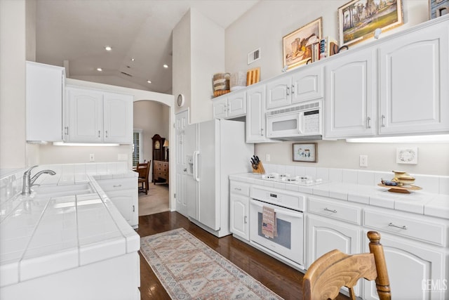 9000 Willamette Ct, Bakersfield, CA 93312 - kitchen with white appliances, tile countertops, recessed lighting, arched walkways, and white cabinets
