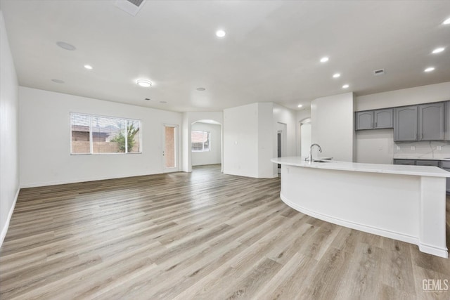 kitchen with light wood-type flooring, sink, gray cabinetry, and decorative backsplash