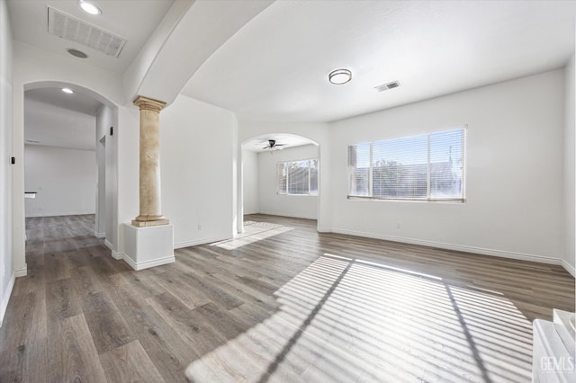 interior space featuring decorative columns, ceiling fan, and wood-type flooring