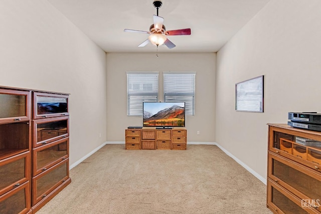interior space featuring light colored carpet, baseboards, and ceiling fan