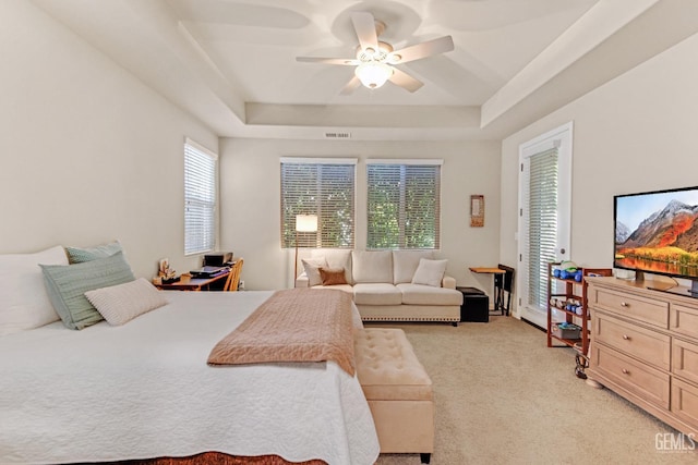 bedroom featuring visible vents, ceiling fan, a tray ceiling, and light carpet