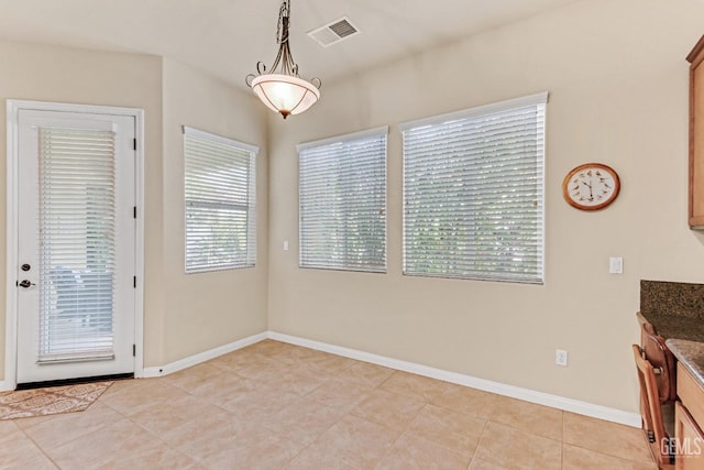 unfurnished dining area featuring light tile patterned floors, baseboards, and visible vents