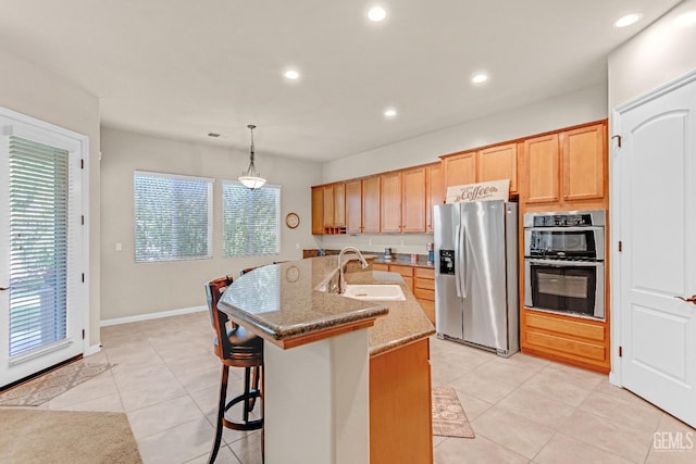 kitchen with a kitchen breakfast bar, a sink, light tile patterned floors, stainless steel appliances, and recessed lighting