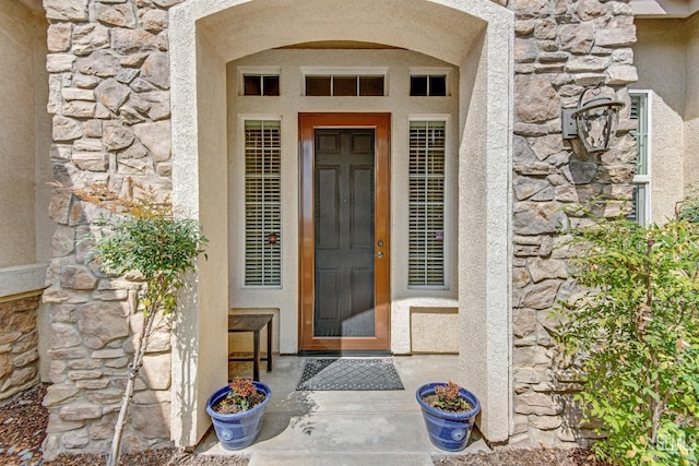 entrance to property featuring stucco siding and stone siding