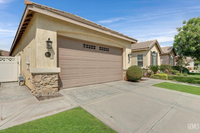 ranch-style home featuring an attached garage, driveway, stone siding, and stucco siding