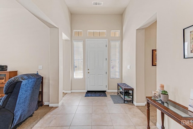 entrance foyer with baseboards, a towering ceiling, light tile patterned flooring, and visible vents