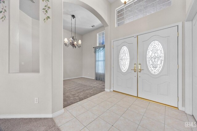 10611 Fishers Peak Dr, Bakersfield, CA 93312 - carpeted entrance foyer featuring arched walkways, a chandelier, tile patterned floors, and a high ceiling