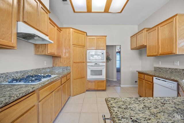 10611 Fishers Peak Dr, Bakersfield, CA 93312 - kitchen with white appliances, under cabinet range hood, light stone countertops, and light tile patterned flooring