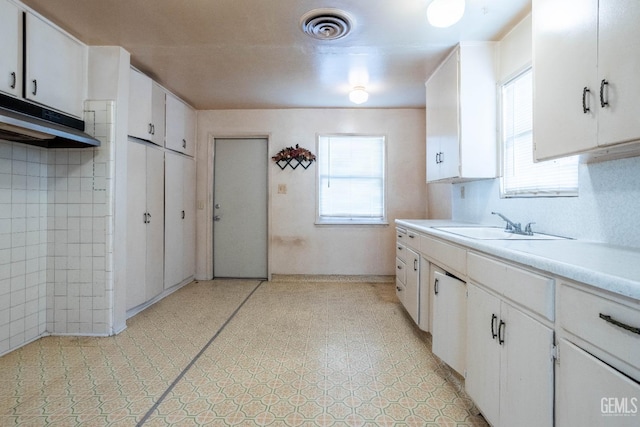 kitchen featuring light floors, light countertops, visible vents, white cabinets, and a sink