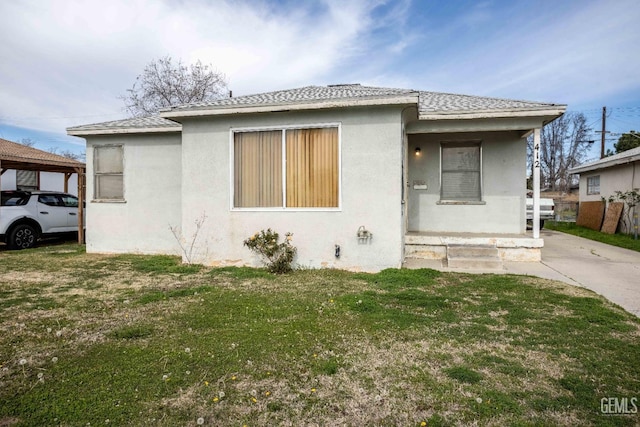 bungalow with a front lawn and stucco siding