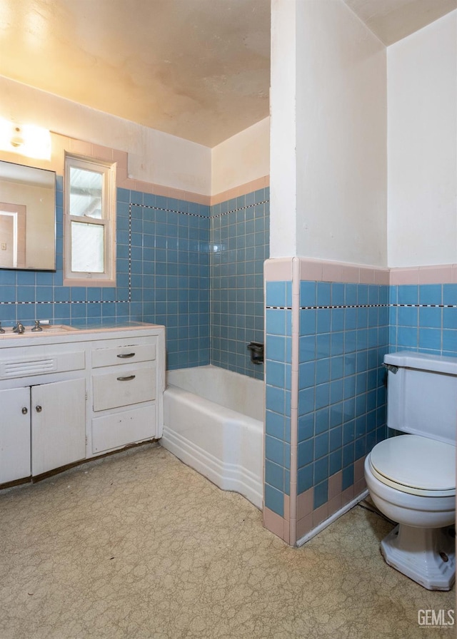 full bath featuring a wainscoted wall, tile walls, toilet, a tub, and tile patterned floors