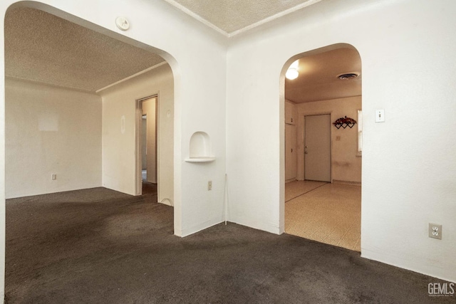 carpeted empty room featuring arched walkways and visible vents