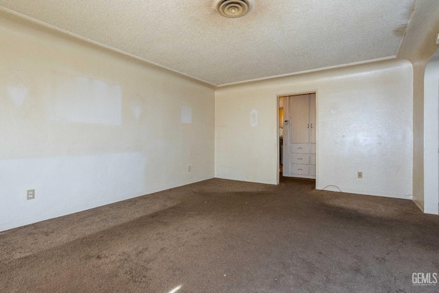 spare room with carpet, visible vents, and a textured ceiling