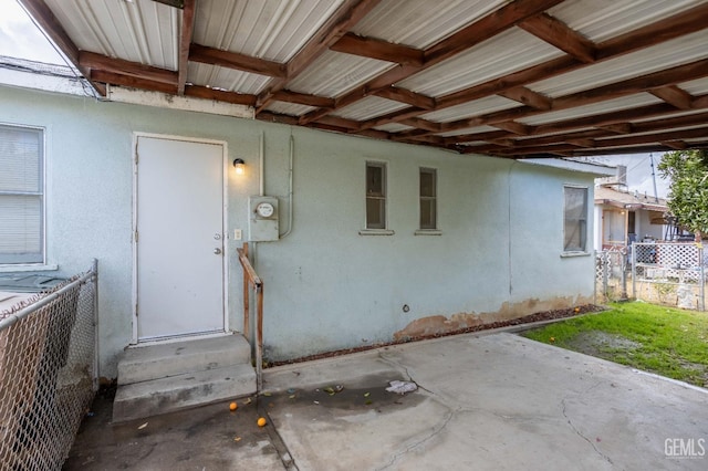 doorway to property featuring fence and stucco siding