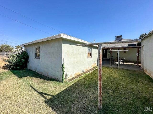 view of side of property featuring a patio, a yard, central AC, and stucco siding