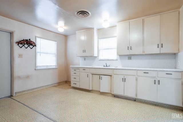 kitchen with light countertops, light floors, a sink, and visible vents