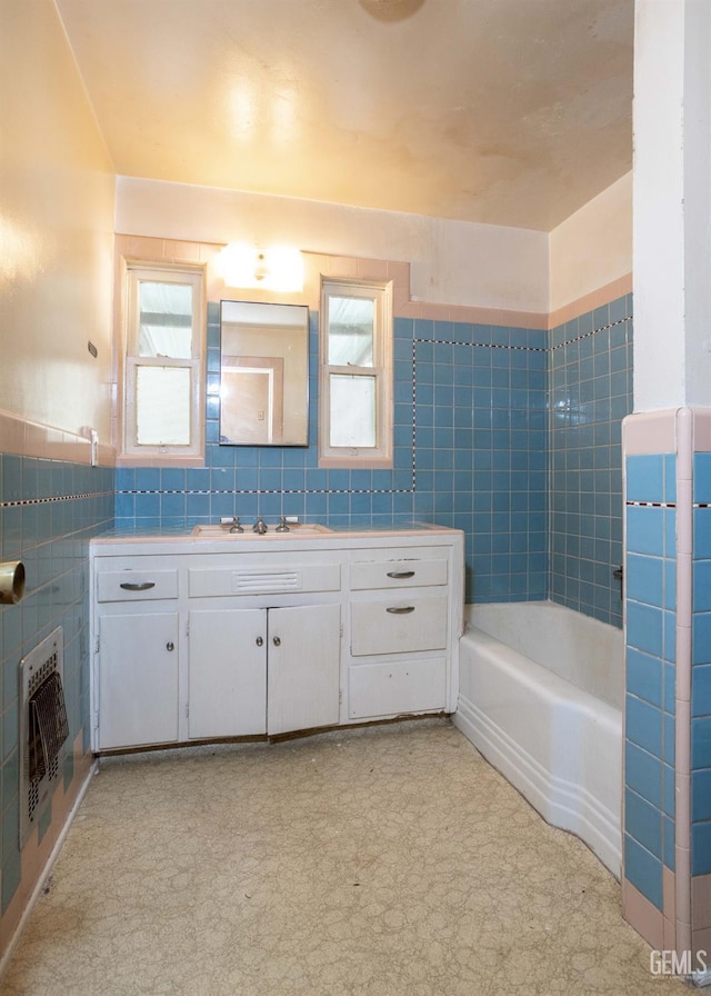 bathroom featuring a bathtub, a wainscoted wall, tile walls, heating unit, and vanity