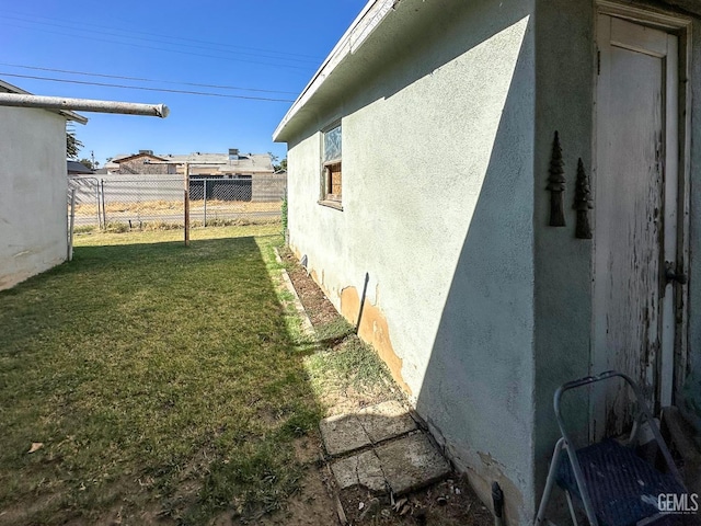 view of property exterior featuring a yard, fence, and stucco siding