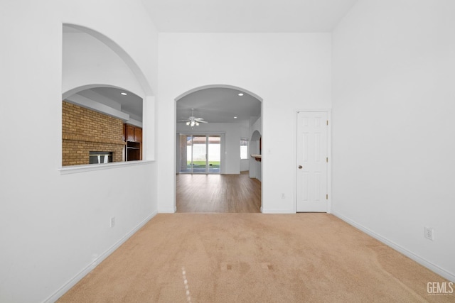 empty room featuring ceiling fan, carpet flooring, and a towering ceiling