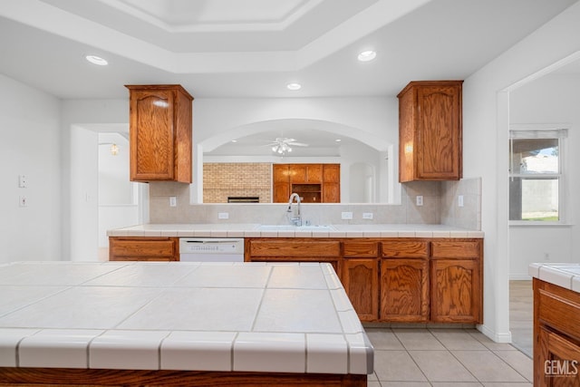 kitchen featuring tasteful backsplash, sink, tile counters, white dishwasher, and a tray ceiling