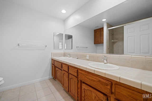 bathroom with tile patterned flooring, vanity, tiled shower, and toilet