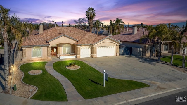 mediterranean / spanish-style home with a yard and a garage