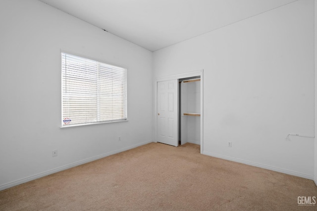 unfurnished bedroom with light carpet and a closet