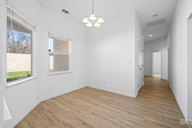 spare room with light hardwood / wood-style floors and a notable chandelier