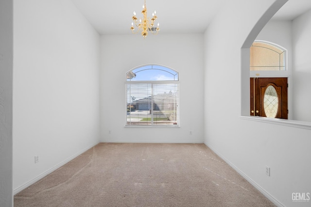 carpeted spare room featuring an inviting chandelier