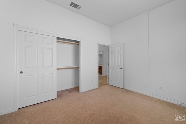 unfurnished bedroom with light colored carpet and a closet