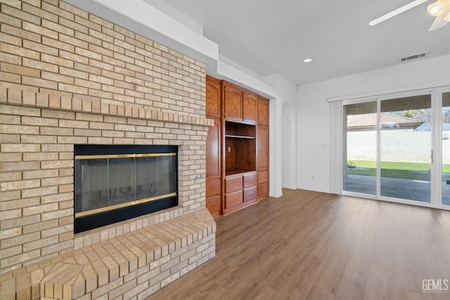 unfurnished living room featuring ceiling fan, hardwood / wood-style floors, and a fireplace