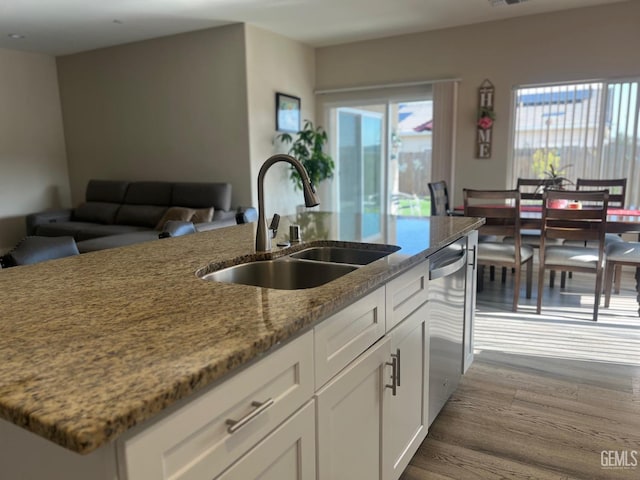 kitchen with white cabinets, dishwasher, light stone countertops, and sink