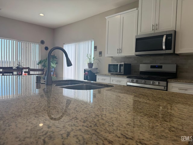 kitchen featuring sink, light stone countertops, white cabinetry, and stainless steel appliances