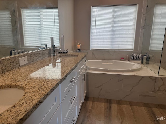 bathroom featuring hardwood / wood-style flooring, vanity, and tiled bath