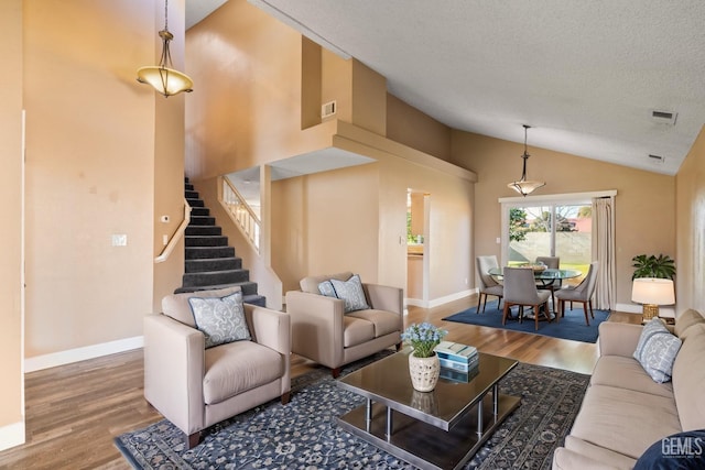 living room with vaulted ceiling, hardwood / wood-style floors, and a textured ceiling