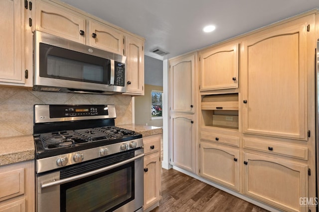 kitchen featuring backsplash, dark wood-type flooring, light brown cabinets, and appliances with stainless steel finishes