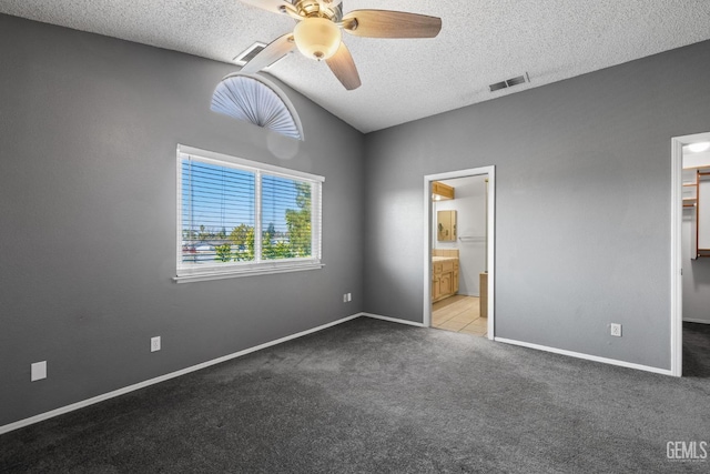 unfurnished bedroom featuring vaulted ceiling, a spacious closet, light colored carpet, and a textured ceiling