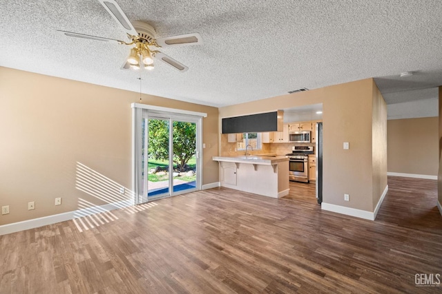 unfurnished living room featuring sink, a textured ceiling, dark wood-type flooring, and ceiling fan