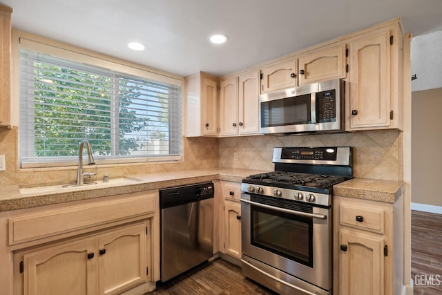 kitchen featuring appliances with stainless steel finishes, sink, backsplash, and dark hardwood / wood-style flooring