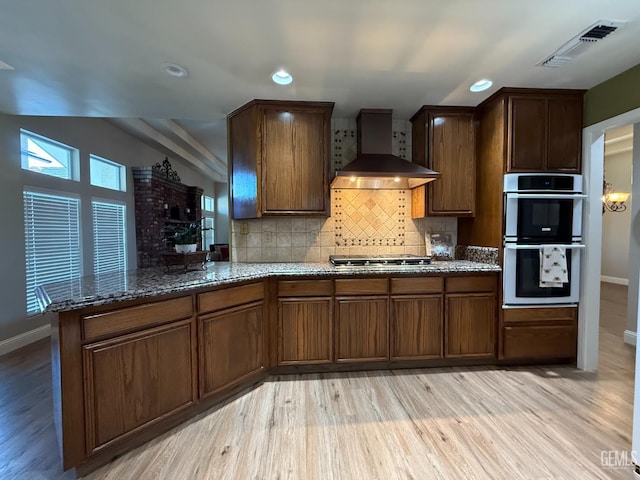 15725 Marty Ave, Bakersfield, CA 93314 - kitchen with wall chimney exhaust hood, appliances with stainless steel finishes, light wood finished floors, dark stone countertops, and recessed lighting
