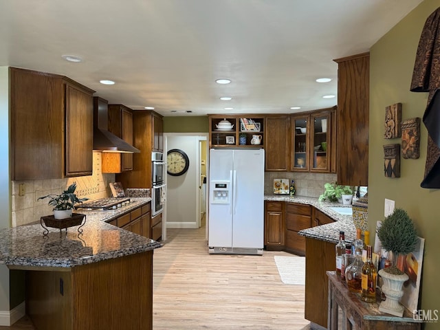 15725 Marty Ave, Bakersfield, CA 93314 - kitchen with appliances with stainless steel finishes, wall chimney exhaust hood, dark stone countertops, open shelves, and a peninsula