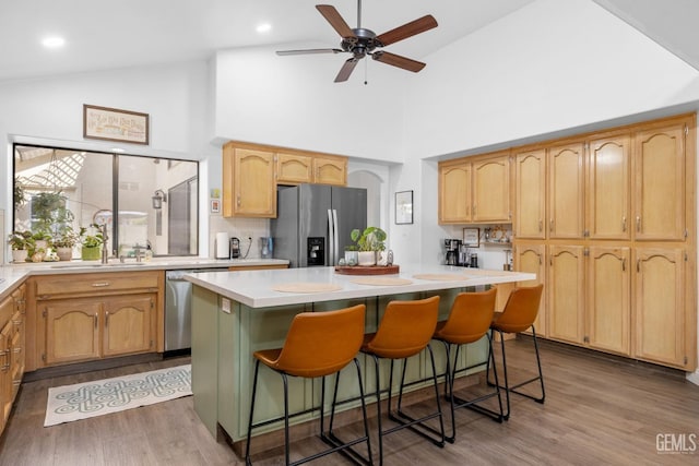 kitchen with sink, a center island, light wood-type flooring, stainless steel appliances, and a breakfast bar area