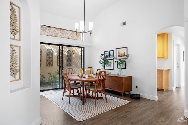 dining space featuring high vaulted ceiling, dark hardwood / wood-style flooring, and a notable chandelier