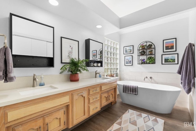 bathroom featuring tile walls, vanity, wood-type flooring, and a bathing tub