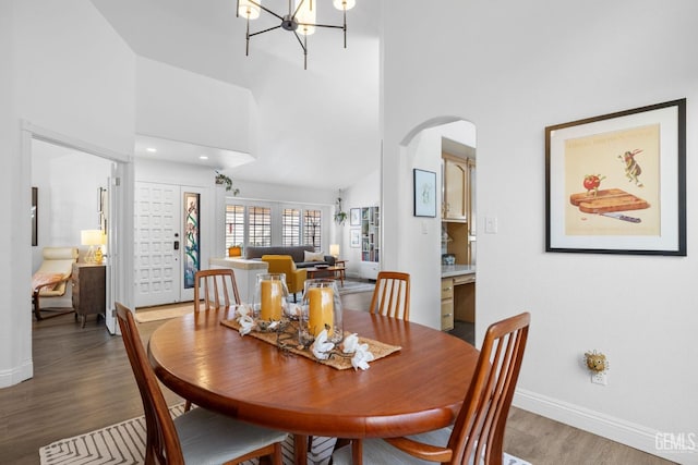 dining area with a high ceiling, hardwood / wood-style floors, and an inviting chandelier