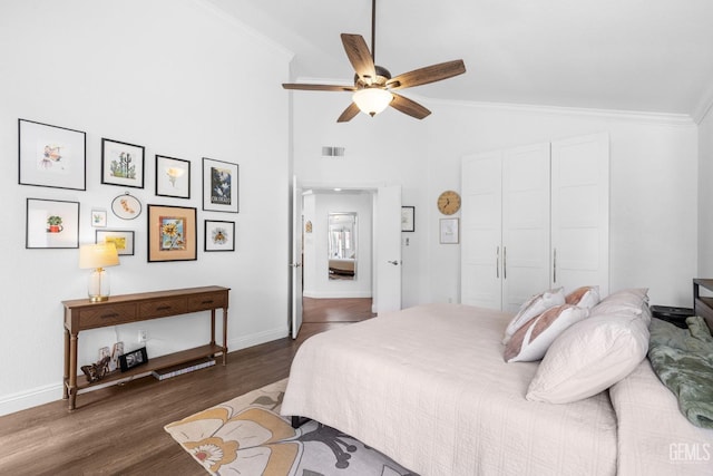 bedroom with lofted ceiling, dark hardwood / wood-style flooring, a closet, ceiling fan, and crown molding