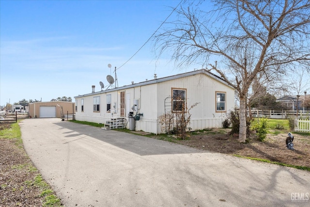 manufactured / mobile home featuring entry steps, a garage, an outdoor structure, fence, and driveway