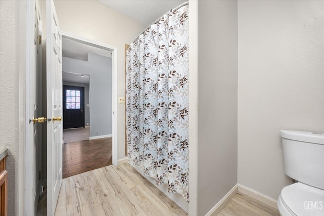 full bath with toilet, baseboards, wood finished floors, and vanity