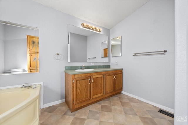 bathroom featuring a garden tub, vanity, visible vents, and baseboards